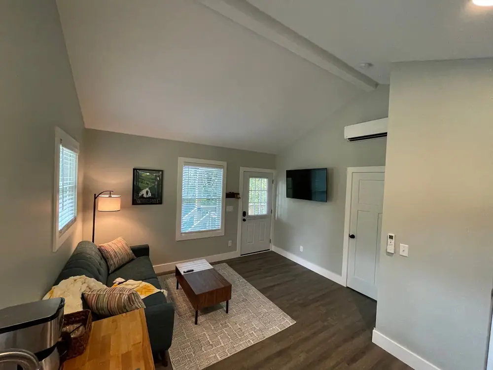 Living room with light gray walls, white doors and trim, and a vaulted ceiling with a beam