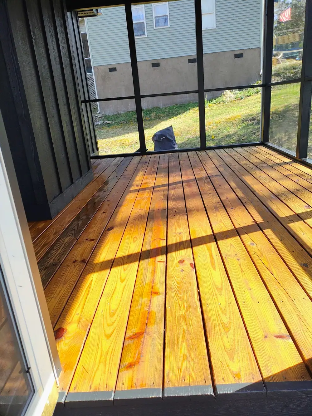 Screened porch with a pine plank floor stained a golden honey tone