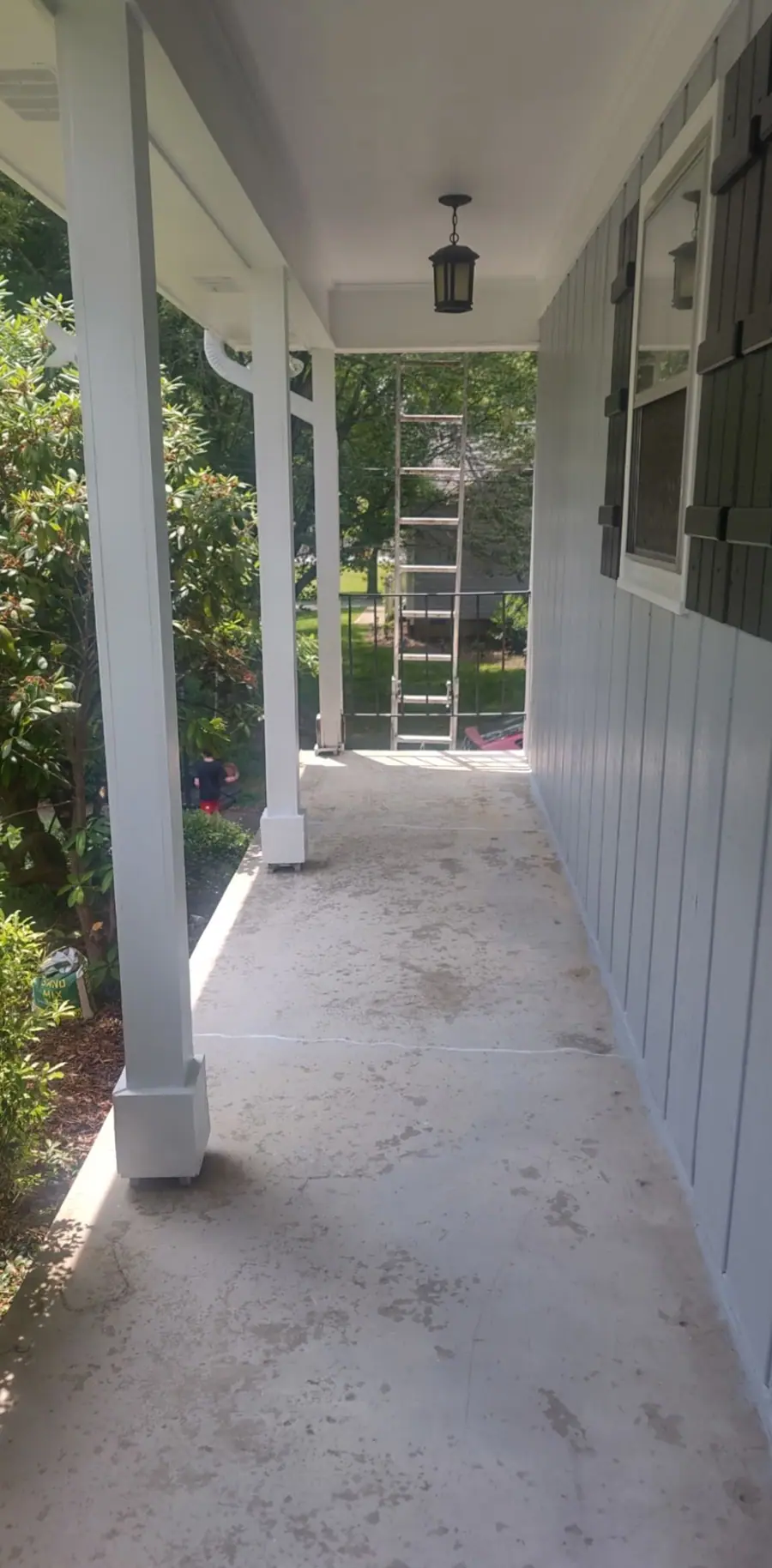 Side porch before, with a bare concrete floor and older blue gray siding