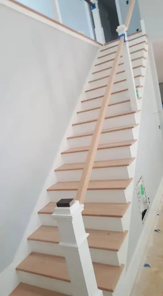 Staircase with white painted risers and skirt board under natural wood treads